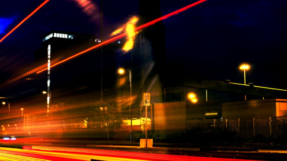 Long-exposure light trails from traffic moving through a city at night.